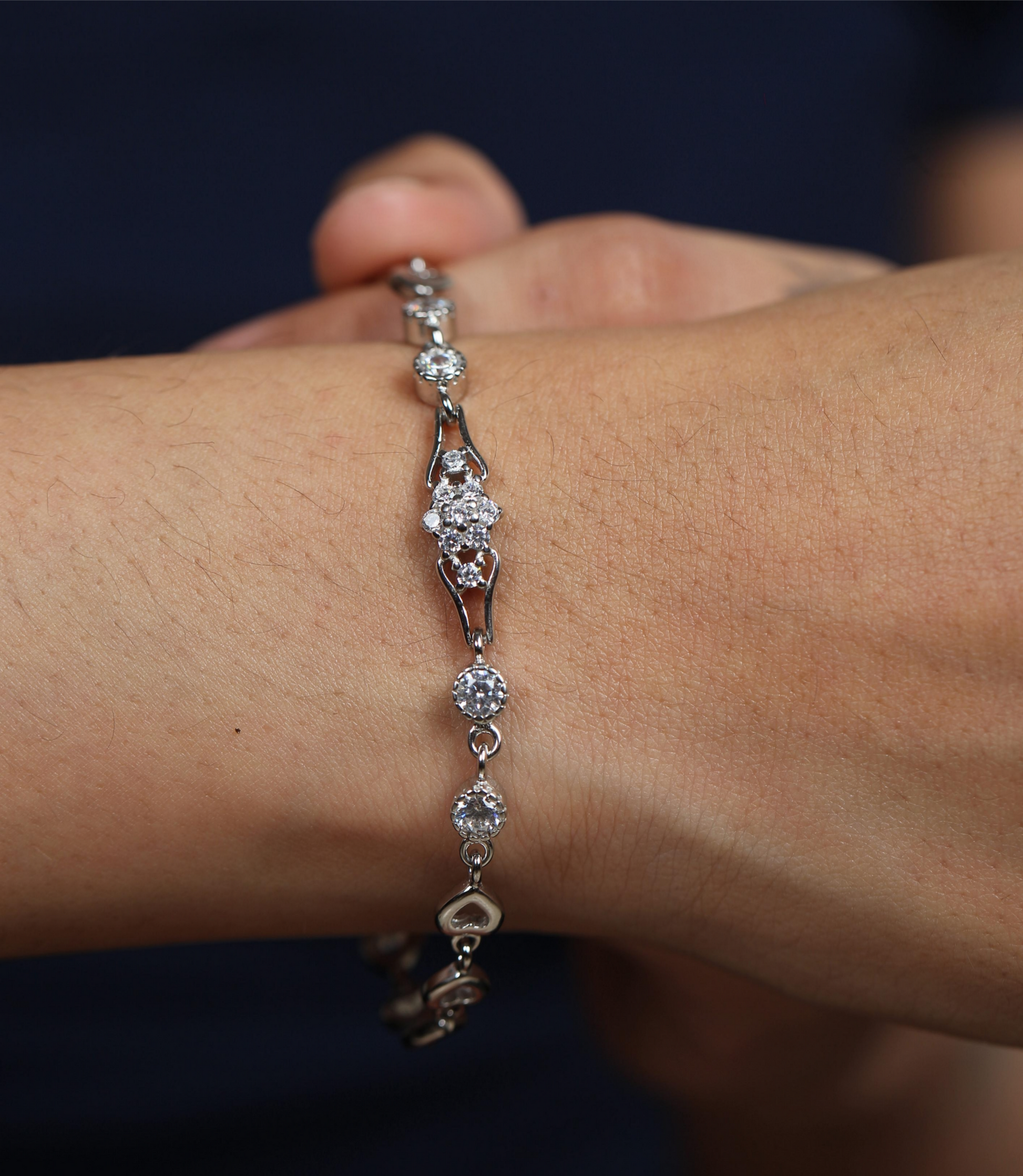 925 silver bracelet worn on wrist with round-cut stones and linked heart accents